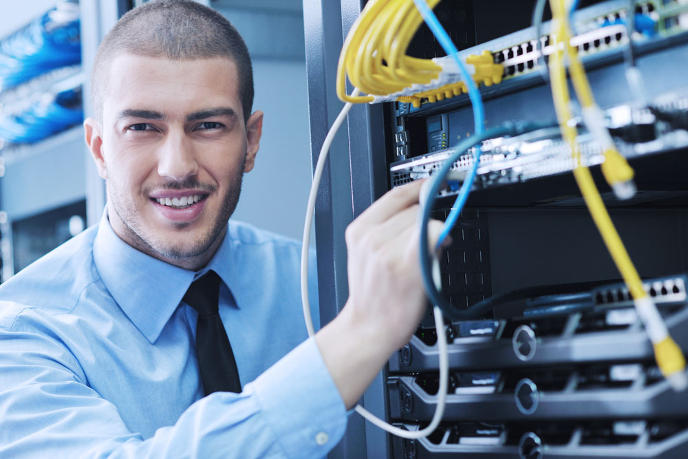 Businessman with laptop in network server room